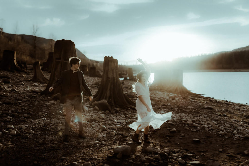Un couple danse au coucher de soleil pour fêter leurs fiançailles. Sa robe blanche vole au vent. Ils sont heureux et ont du fun. Photo prise par Gaétane Glize au pays basque, photographe de couple dans les landes.