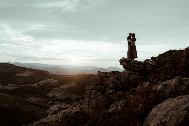 photo d'un couple à la montagne au coucher de soleil. Le couple est sur un rocher et ils s'embrassent pour fêter leurs fiançailles.