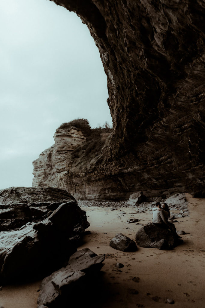 photo de couple au pays basque sur la plage au pied d'une falaise surplombant l'ocean. Séance photo couple et fiançailles dans les landes et le pays basque.