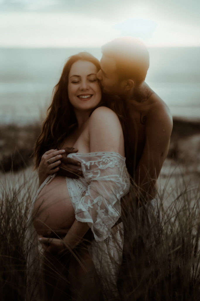 photo d'un couple prise au coucher du soleil pendant une séance photo grossesse.