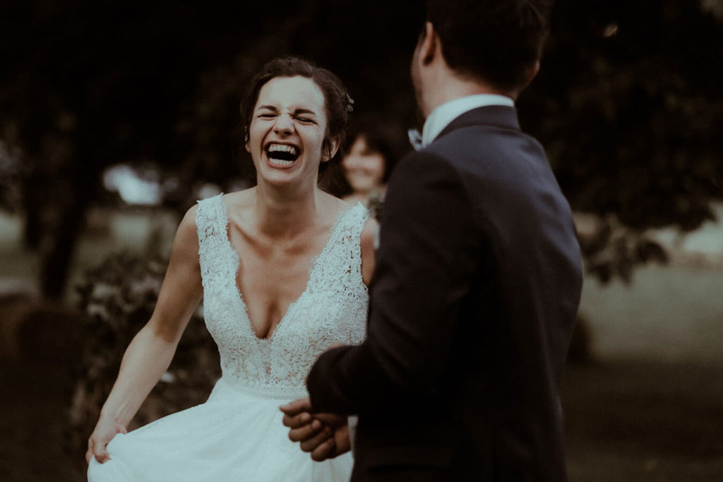 La mariée rigole à gorge déployée pendant le vin d'honneur de son mariage, un moment de joie photographié par Gaétane Glize, votre photographe de mariage en France, en Europe et dans le monde.