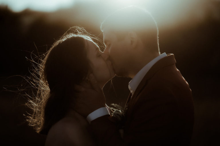 Les mariés s'embrassent tendrement lors de leur séance photo couple au coucher de soleil le jour de leur mariage dans les Landes.