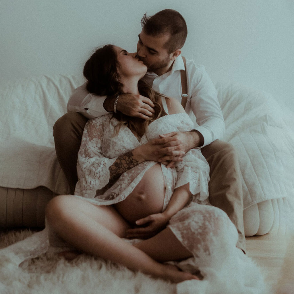 Le couple qui attend un bébé s'embrasse. Un moment de douceur photographié par Gaétane Glize pendant leur séance photo grossesse.
